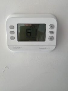 A digital Honeywell Home thermostat displays a temperature of 61°F with a 